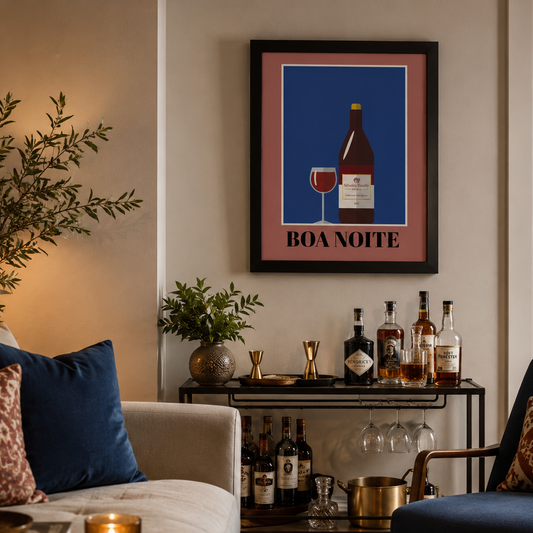 A framed wall art print featuring a wine bottle and glass on a blue background with the text 'BOA NOITE' in Portuguese, displayed in a cozy living room above a bar cart with wine bottles.