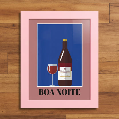 A framed art print featuring a stylized illustration of a wine bottle and a glass of red wine on a blue background, with the text 'BOA NOITE' at the bottom. The print is enclosed in a dusty pink frame and is shown against a plain white background.