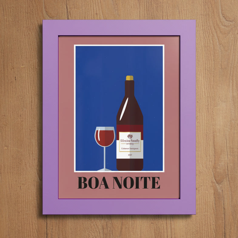 A framed art print featuring a stylized illustration of a wine bottle and a glass of red wine on a blue background, surrounded by a dusty pink inner frame and a lavender outer frame. The text 'BOA NOITE' is printed at the bottom.