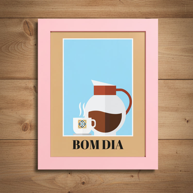 A framed art print with a light pink frame and tan mat, featuring a minimalist illustration of a white coffee mug and a white coffee carafe with brown coffee on a light blue background, with the text 'BOM DIA' printed below.