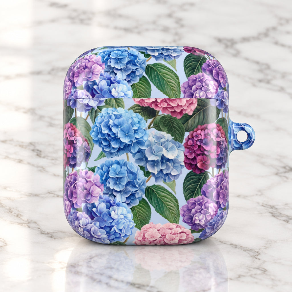 A protective case for wireless earbuds featuring a vibrant floral print of blue, purple, and pink hydrangeas with green leaves on a light background, complete with a blue transparent loop on the side.