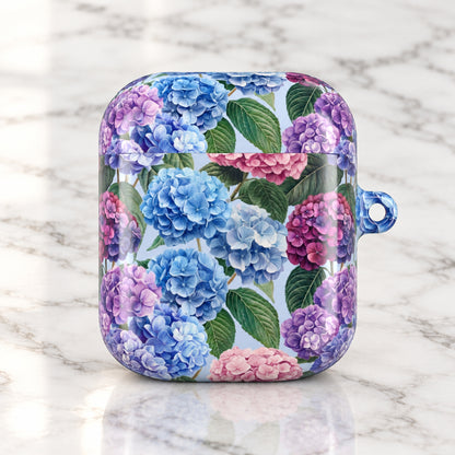 A protective case for wireless earbuds featuring a vibrant floral print of blue, purple, and pink hydrangeas with green leaves on a light background, complete with a blue transparent loop on the side.