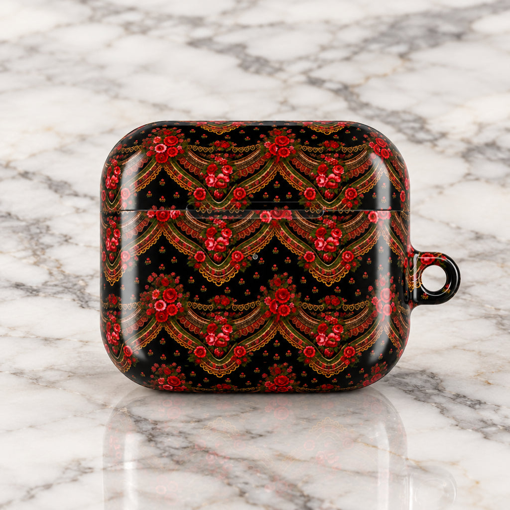 A protective case for an AirPods charging case, featuring a glossy black background with an intricate, symmetrical red and gold floral pattern, and a small metal loop on the right side.