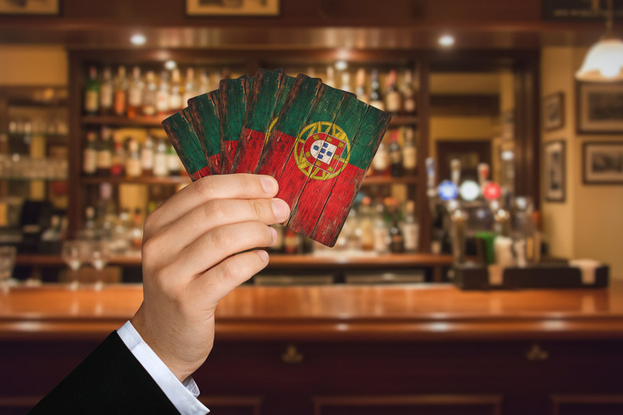 Hand holding a set of playing cards with a Portuguese flag design on a white background